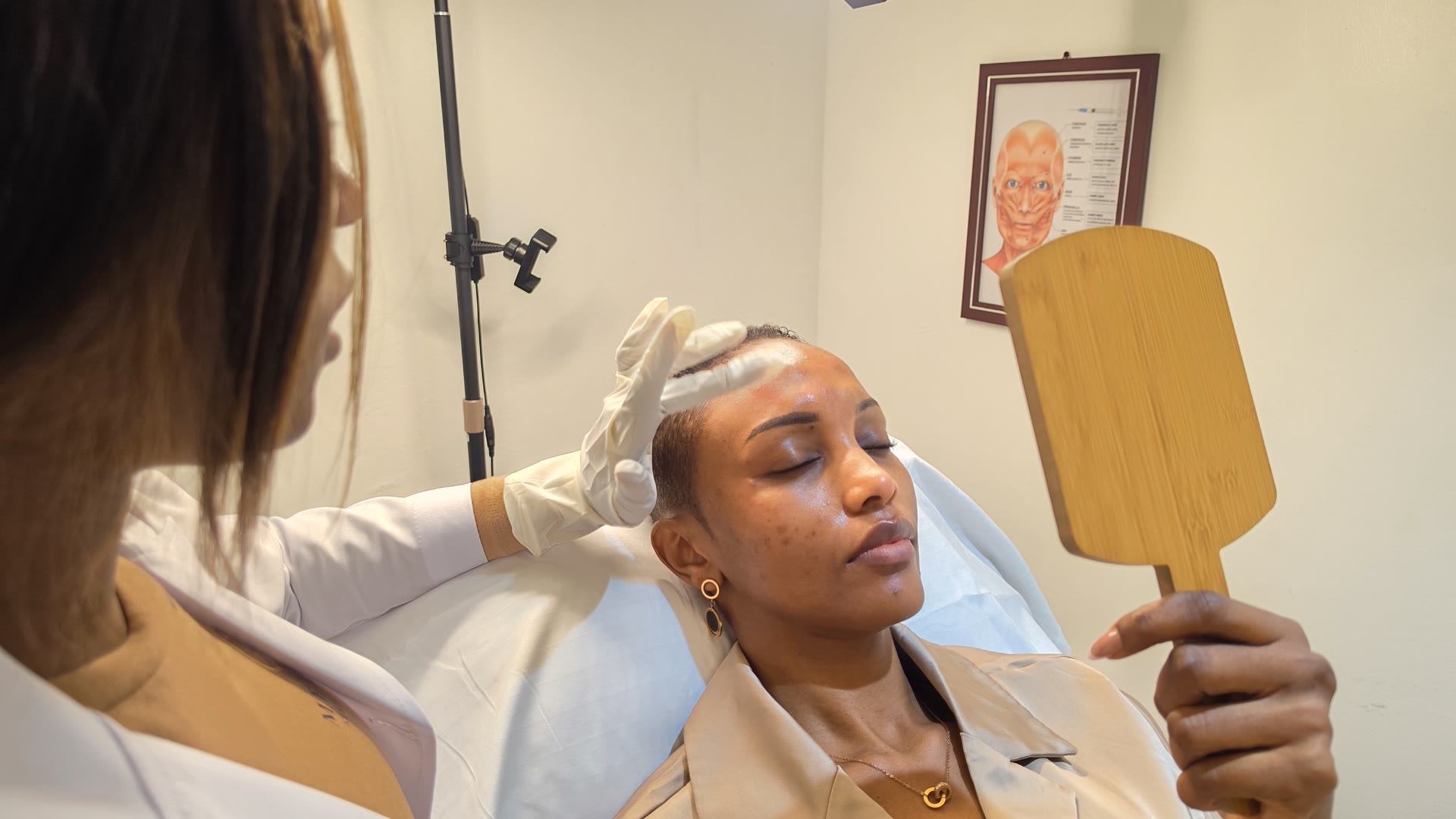 Gloved clinician examining a client’s facial skin during a dermatology assessment at Melton